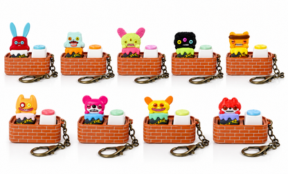 Fuggler × JAKA Laboratory Escape Plan Series showing nine colourful miniature monster keycap designs with brick-pattern bases and metal keychain attachments.