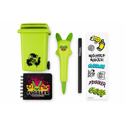 Fuggler stationery gift set contents arranged on a white background, including a lime-green wheelie bin stationery pot, green rabbit novelty pen, black Fuggler pencil, mini spiral notebook and colourful Fuggler sticker sheet.