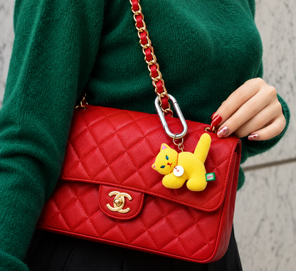 Yellow Gyunyuya Japanese artist cat mascot attached to a red quilted Chanel handbag, demonstrating the collectible figure as a stylish bag charm.