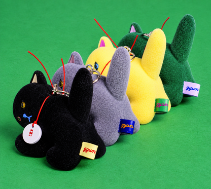 Four Gyunyuya Japanese designer cat mascots arranged together on a green background, showing their raised tails and colourful fabric labels.