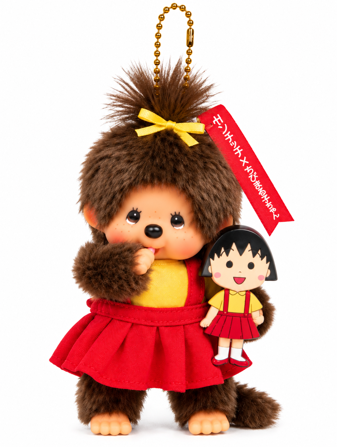 Monchhichi × Chibi Maruko-chan plush keychain wearing a yellow top, red pleated skirt and yellow hair bow, holding a miniature Maruko doll against a white background.