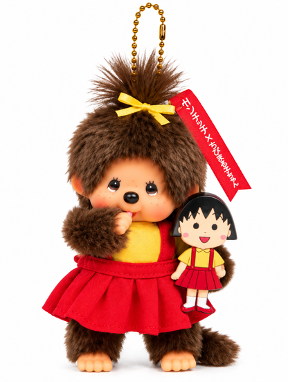 Monchhichi × Chibi Maruko-chan plush keychain wearing a yellow top, red pleated skirt and yellow hair bow, holding a miniature Maruko doll against a white background.