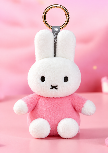 Adorable VIPO Miffy pink plush bunny bag charm featuring soft white fur, pastel pink outfit and gold-tone keyring against a dreamy pink background.