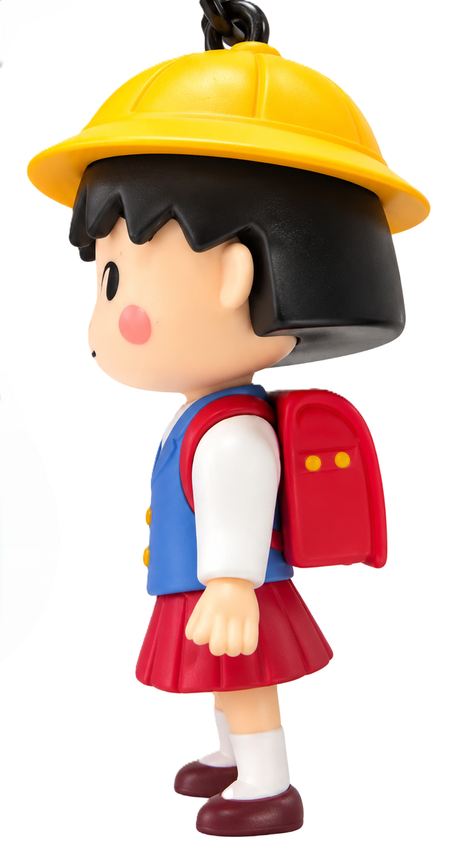 Side view of Chibi Maruko Chan collectible figure keyring showing her yellow school hat, black bob hairstyle, red backpack and school uniform.