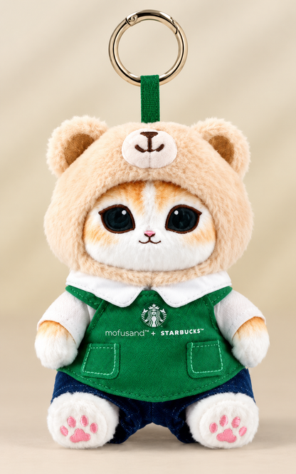 Starbucks × Mofusand Singapore-exclusive 2026 ginger cat Bearista plush keychain wearing a beige teddy bear hood, green Starbucks apron and navy shorts.