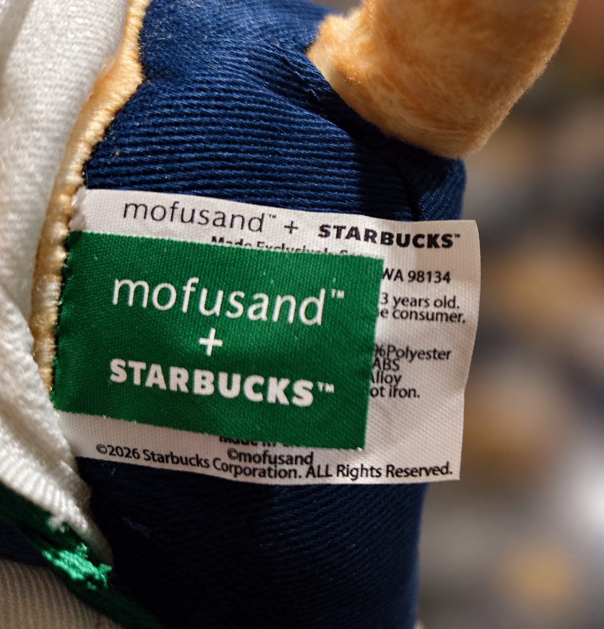 Close-up of the original Starbucks × Mofusand plush keychain fabric labels showing official collaboration branding and 2026 copyright information.