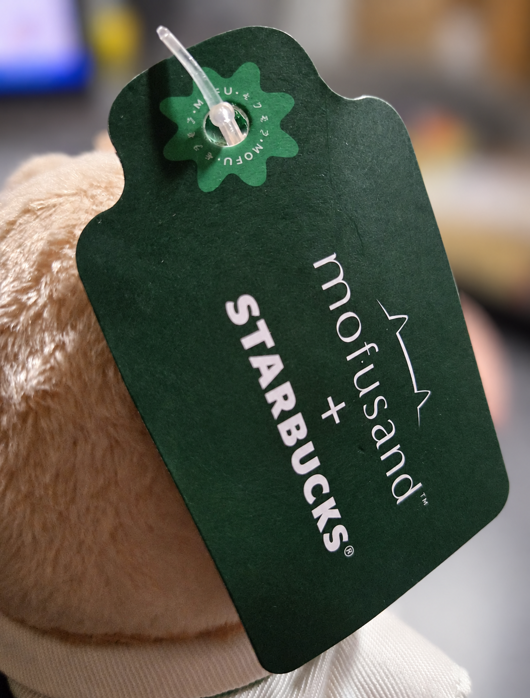 Original dark green Starbucks × Mofusand collaboration swing tag attached to the limited-release ginger cat Bearista plush keychain.
