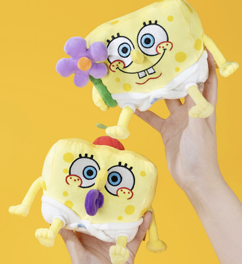 Pop Mart × SpongeBob SquarePants Friends Play Together collectible plush keychains featuring two SpongeBob designs, including SpongeBob holding a purple flower, displayed against a yellow background.